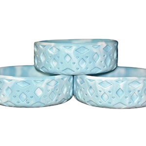 May include: Three light blue silicone bowls with a diamond pattern. The bowls are stacked on top of each other.
