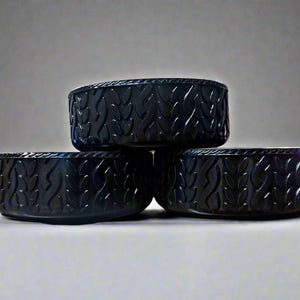 May include: Three black, round bowls with a leaf-like pattern carved into the sides. The bowls are stacked, with two on the bottom and one on top. The bowls have a glossy finish and are set against a neutral background.
