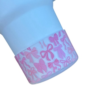May include: A close-up of a white silicone cup with a pink and white bow pattern around the rim.
