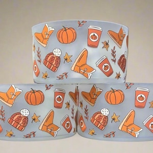 May include: Three frosted glass candle holders with a repeating pattern of orange pumpkins, boots, coffee cups, and fall leaves on a light blue background. The design evokes a cozy autumn theme.