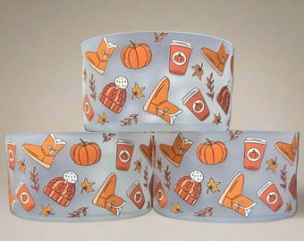 May include: Three frosted glass candle holders with a repeating pattern of orange pumpkins, boots, coffee cups, and fall leaves on a light blue background. The design evokes a cozy autumn theme.