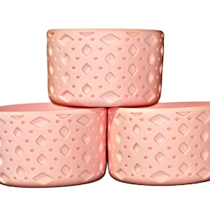 May include: Three pink silicone rings with a diamond pattern. The rings are stacked on top of each other.