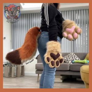 May include: A furry costume set featuring a fox tail and paw gloves. The tail is orange and brown, and the gloves are tan with pink and brown paw pads. The costume is designed for cosplay or themed events.
