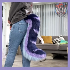 May include: A faux fur tail in shades of blue, purple, and white is attached to the back of a person's jeans. The tail is fluffy and has a striped pattern. The tail is a costume accessory.