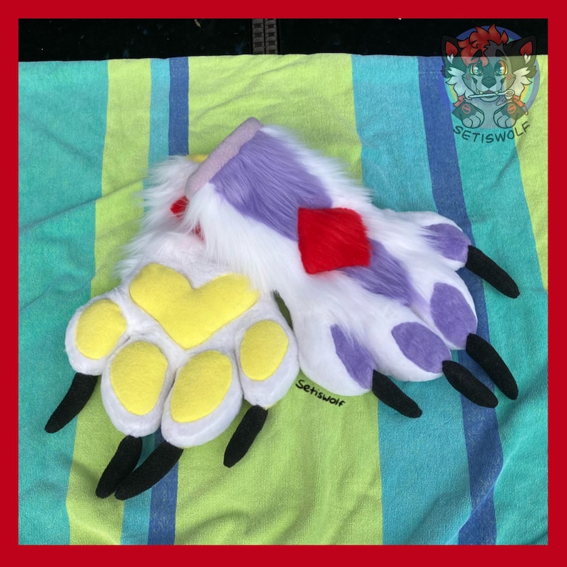 May include: A pair of plush animal paw gloves featuring white faux fur with purple accents, yellow paw pads, and black claws. A red diamond-shaped patch is visible on the back of one paw. The text Setiswolf is printed on the fabric near the claws.