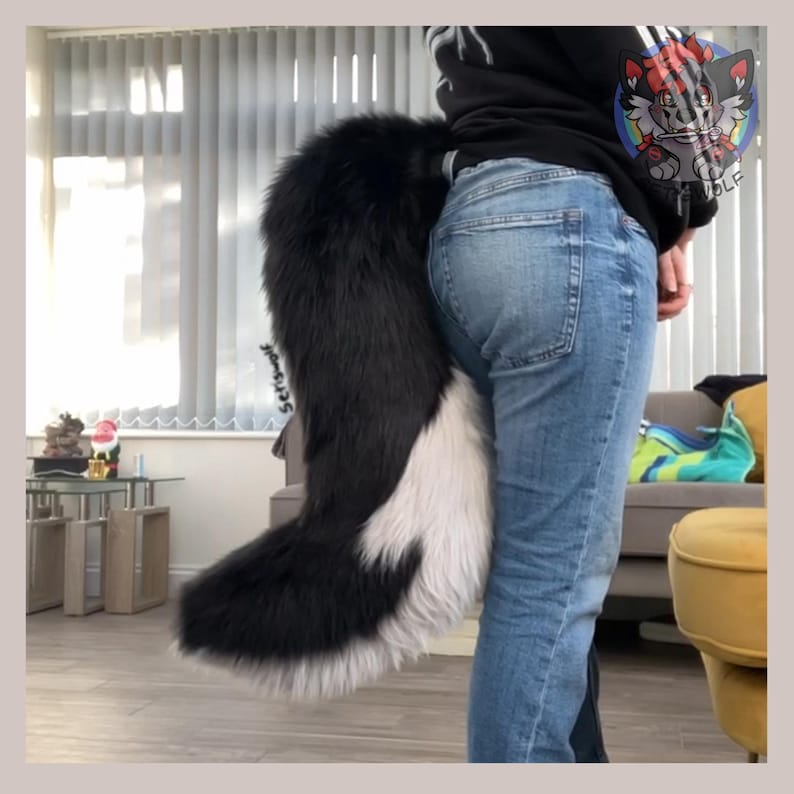 May include: A black and white faux fur tail, attached to the back of a person wearing blue jeans. The tail is fluffy and has a curved shape, with a black top and a white bottom. The tail is a costume accessory.