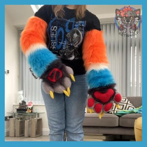 May include: A pair of long, plush faux fur arm sleeves featuring a color-blocked pattern of bright orange, white, and blue. The attached paw-shaped gloves are dark gray with red paw pads and sharp, yellow claws. The text Setiswolf is visible.
