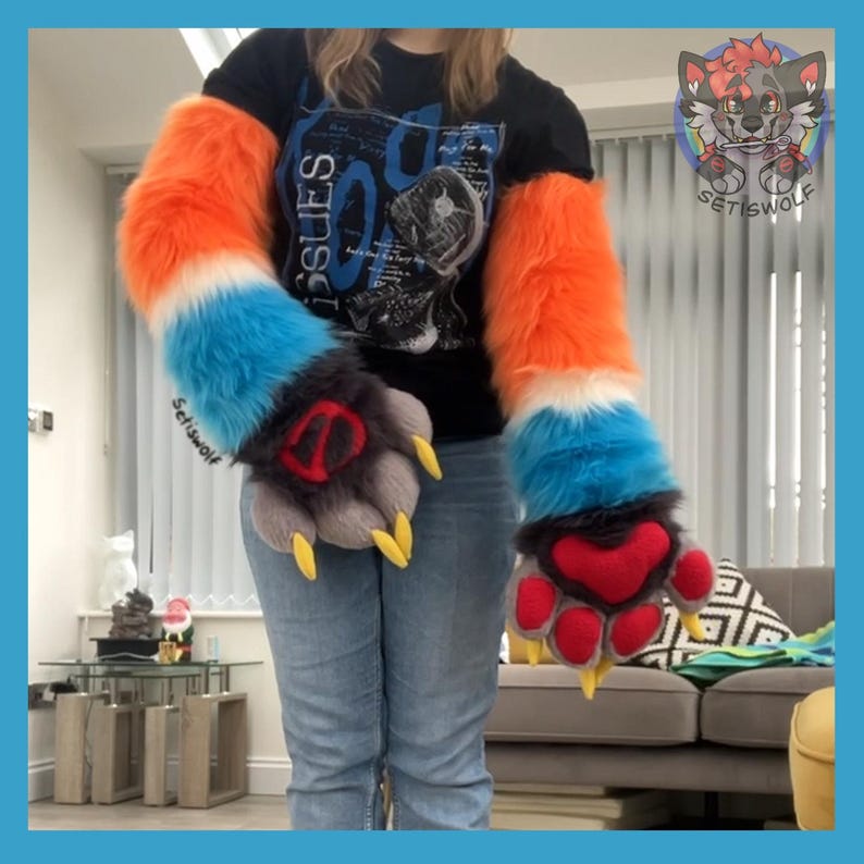 May include: A pair of long, plush faux fur arm sleeves featuring a color-blocked pattern of bright orange, white, and blue. The attached paw-shaped gloves are dark gray with red paw pads and sharp, yellow claws. The text Setiswolf is visible.