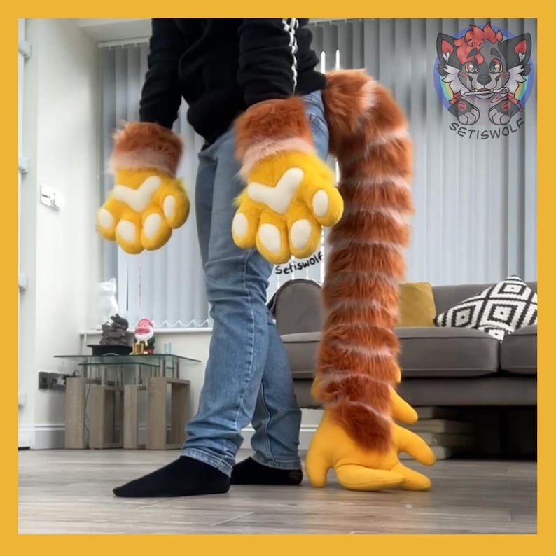 May include: A furry costume set featuring orange and yellow paw gloves and a long, matching tail. The gloves have white accents and the tail is striped. The set is designed to resemble a cartoon animal.