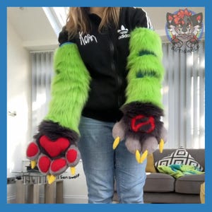 May include: A pair of long, lime green faux fur arm sleeves with dark gray fur accents at the wrists. The hand portions feature dark gray fur, bright red paw pads, and sharp yellow claws. One paw pad is heart-shaped, and the other has a red symbol.