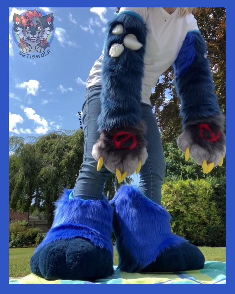 May include: A pair of long, dark blue faux fur arm sleeves with white paw pads and yellow claws, featuring red circular accents on the wrists. Matching oversized dark blue faux fur foot covers with a thick, plush texture are also included.