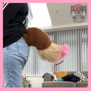 May include: A brown, tan, and pink faux fur tail attached to a person's waist. The tail is fluffy and has a gradient of colors, transitioning from brown to tan and ending in a pink tip. The tail is part of a costume.