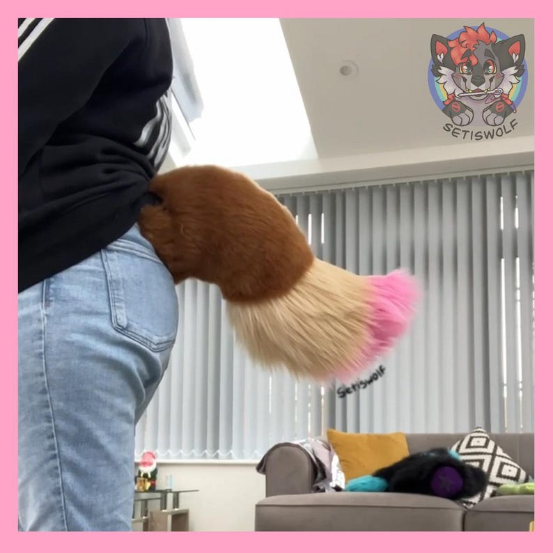 May include: A brown, tan, and pink faux fur tail attached to a person's waist. The tail is fluffy and has a gradient of colors, transitioning from brown to tan and ending in a pink tip. The tail is part of a costume.