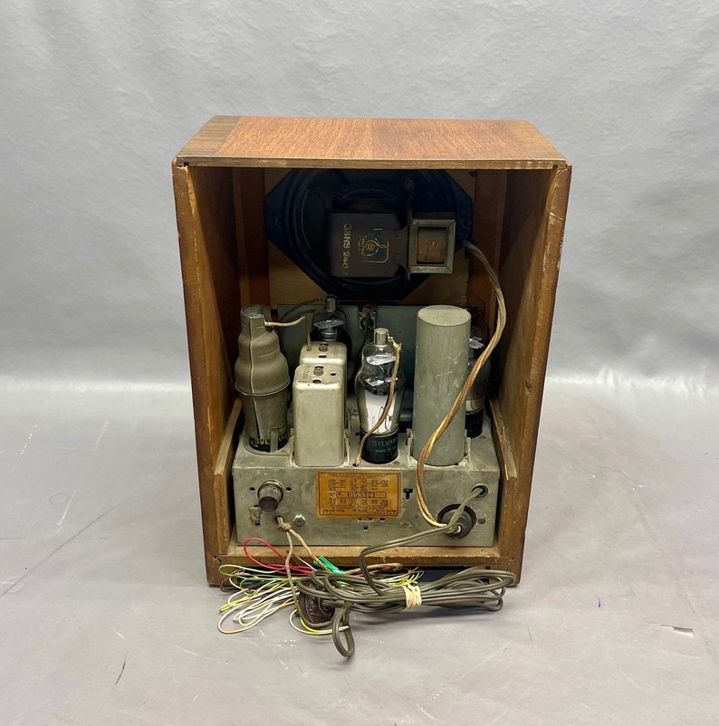 May include: The back of a vintage wooden radio with a speaker, multiple vacuum tubes, and a label that reads "Model 500, 5 Tube Superheterodyne Receiver, AC-DC, 110-120 Volts, 60 Cycles, Made in USA".