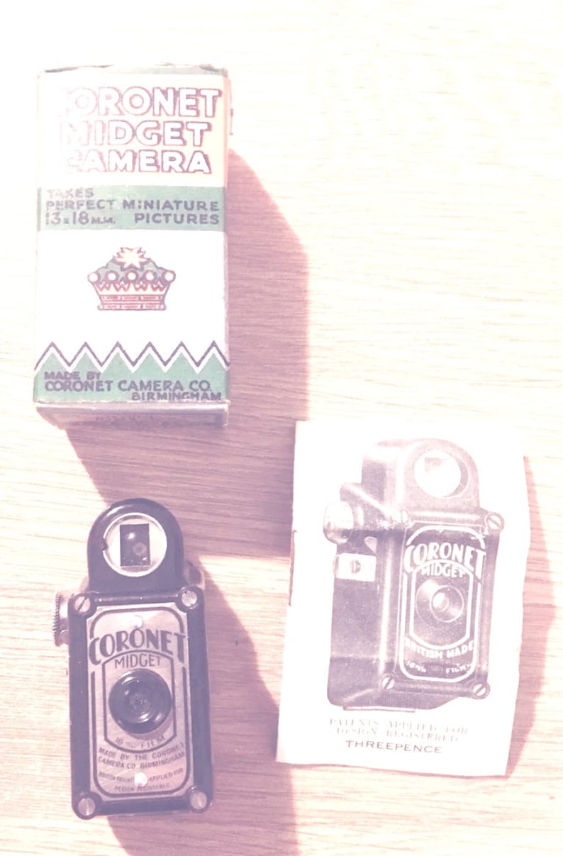 May include: A vintage Coronet Midget camera with a black and silver body. The camera is 13x18 mm and takes perfect miniature pictures. The box is green and white with a crown logo and the text "Coronet Midget Camera".