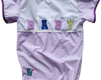 ABDL onesie. Non stretch cotton.  Snap crotch. BABY logo and dinosaur. Lilac & white body, lilac white trim. Appliques. Sweet, cute