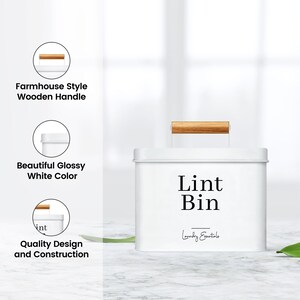 May include: White metal lint bin with a wooden handle. The bin has a black label that says "Lint Bin" and "Laundry Essentials".