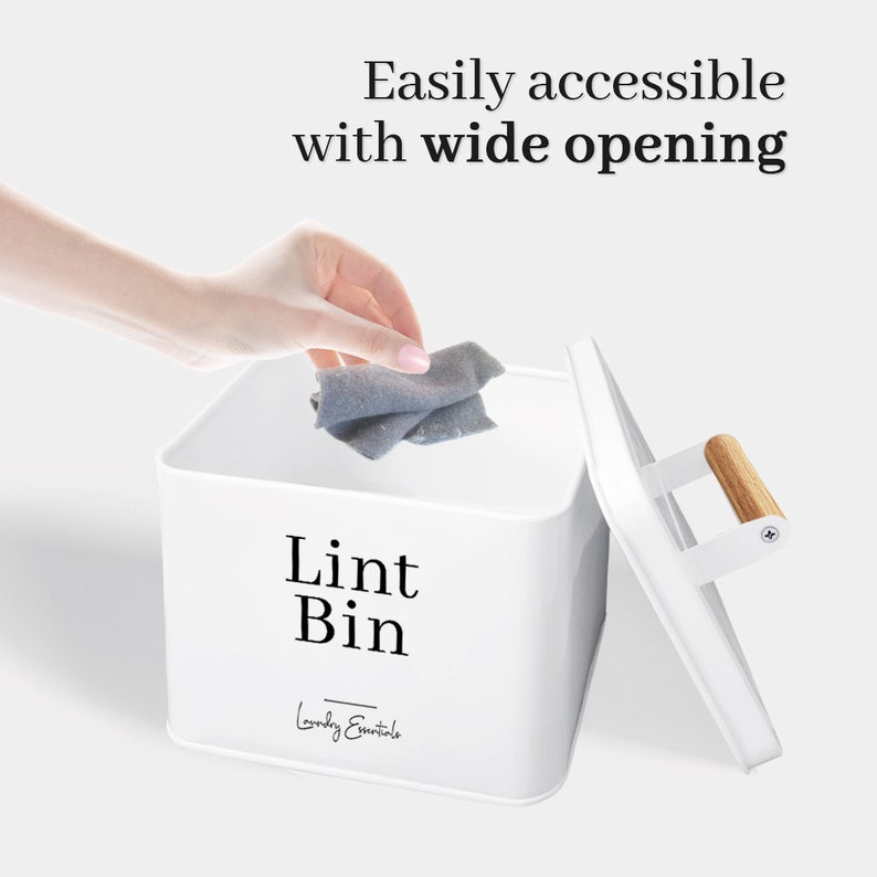 May include: White metal lint bin with a wooden handle and the text "Lint Bin" and "Laundry Essentials". A hand is placing a gray lint cloth into the bin.