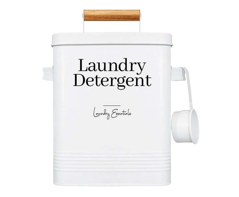 May include: White metal laundry detergent container with a wooden handle and a scoop. The container has the text "Laundry Detergent" and "Laundry Essentials" printed on it.