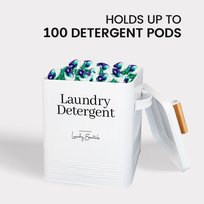 May include: White metal container with a lid, labeled "Laundry Detergent" and "Laundry Essentials". The container is filled with laundry detergent pods and has a text overlay that reads "Holds up to 100 Detergent Pods".