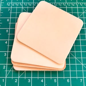 Può includere: Un mucchio di quattro quadrati di pelle rosa chiaro su un tappetino da taglio verde.