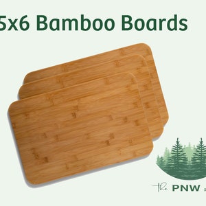 May include: Three 8.5x6 inch bamboo cutting boards stacked on top of each other. The boards are made of natural bamboo and have a light brown color.