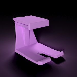 Könnte beinhalten: Ein fester, lavendelfarbener Ständer mit rechteckiger Oberseite und gebogener Stütze. Der Ständer hat unten einen Schlitz und ist zur Aufnahme eines Gegenstands bestimmt. Der Hintergrund ist schwarz.