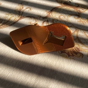 Angled build plate drain hanger for Elegoo Mars resin 3D printer shown in multiple colors, 3D printed resin drip holder accessory designed to hold the build plate at an angle for draining resin back into the vat, compatible with Elegoo Mars, Mars Pro and Mars 3