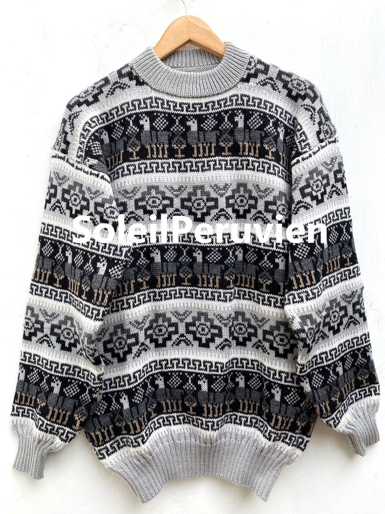 May include: A gray, black, and beige alpaca sweater with a geometric pattern. The sweater has a crew neck and long sleeves.