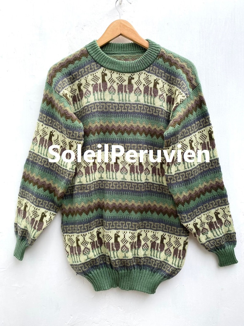 May include: A green, brown, and cream striped sweater with a llama pattern. The sweater has a crew neck and long sleeves. The text "Soleil Peruvien" is printed on the front of the sweater.