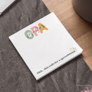 May include: A white notepad with the text "Angie Smith" and "Oh... this calls for a spreadsheet" printed on it. The notepad is 4 inches by 4 inches.