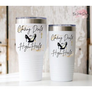 May include: Two white stainless steel tumblers with a gold and black design. The tumblers feature the text "Closing Deals in High Heels" with a pair of black high heels and a gold key.