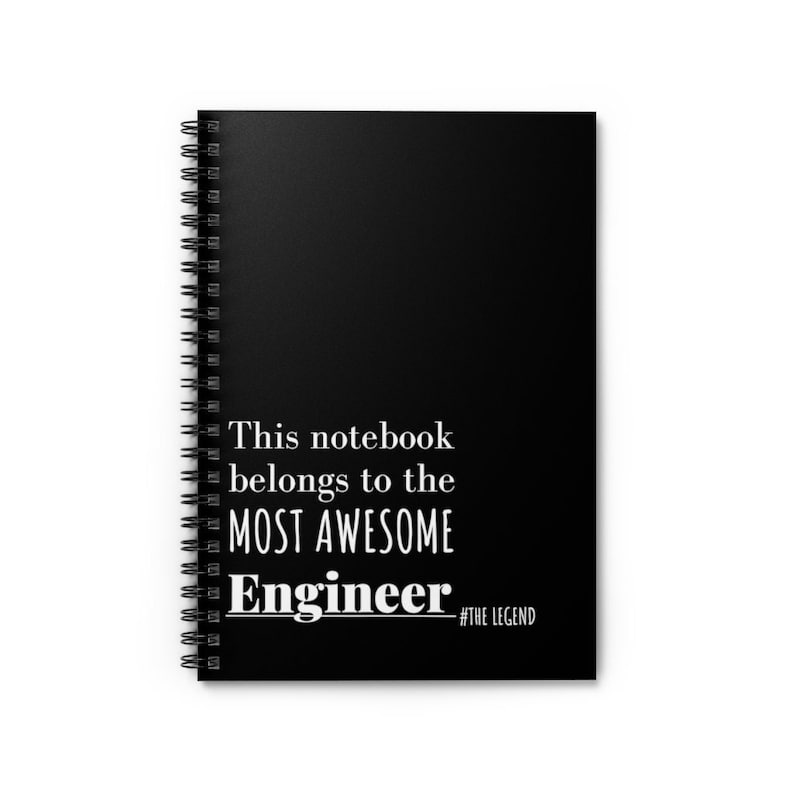 May include: Black spiral-bound notebook with white text that reads "This notebook belongs to the MOST AWESOME Engineer #THE LEGEND". The notebook is a standard size and has a black cover.