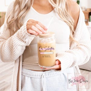 May include: A clear glass tumbler with a wooden lid and a straw. The tumbler has a pink and white progress bar with the text "Dr Schaffer in progress..." printed on it.