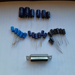 May include: A collection of blue and black electronic capacitors with silver leads, and a silver 9-pin connector.