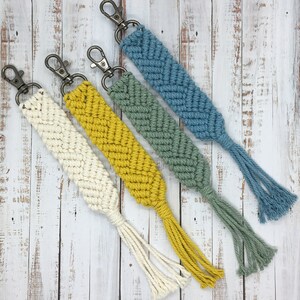Peut inclure: Quatre porte-clés en macramé avec des glands. Les porte-clés sont dans des tons de bleu, vert et jaune.