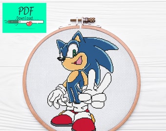 May include: Cross-stitch pattern of Sonic the Hedgehog in a wooden embroidery hoop. Sonic is blue with white gloves and red shoes. He is smiling and giving a peace sign.