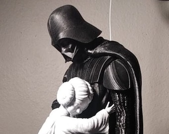 May include: A black and white sculpture of Darth Vader embracing Princess Leia. Vader is in his iconic helmet and armor, while Leia is in a white gown. The figures are detailed and stand in a neutral setting.
