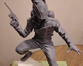 May include: A gray, futuristic-looking action figure with a helmet, a jetpack, and a gun. The figure is standing on a platform, with one leg raised and the other bent. The figure is made of plastic and has a detailed design.