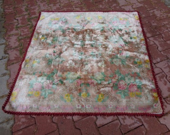 Könnte beinhalten: Ein Vintage-Blumenteppich mit einem verblassten rosa, grünen und braunen Muster. Der Teppich hat einen roten Fransenrand.