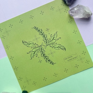 May include: A green print with a black and white illustration of a stylized plant with the text "THE WHITE HORSE SPIRIT" in a white rectangle.