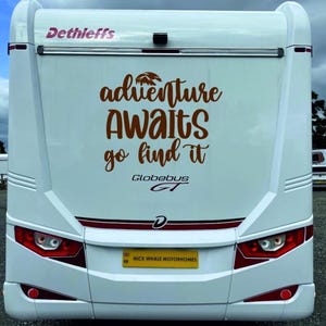 以下が含まれることがあります： 茶色のスクリプトで「adventure awaits go find it」というテキストが入った白いキャンピングカー。車両には赤と白のアクセントがあり、上部にはブランド名「Dethleffs」があります。ナンバープレートには「NICK WHALE MOTORHOMES」と書かれています。