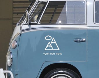 May include: A white mountain and cloud graphic sticker on a blue and white vintage van. The sticker has the text "YOUR TEXT HERE" below the graphic. The van has a black tire and chrome accents.