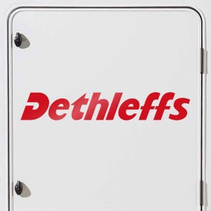 May include: A white panel featuring the red word "Dethleffs". The panel has black hinges and a latch. The text is in a bold, sans-serif font. The panel is likely part of a vehicle.