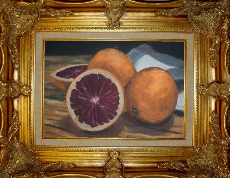 K&ouml;nnte beinhalten: Ein Stillleben mit drei Orangen, zwei mit orangefarbener Schale und eine mit tiefrotem Inneren, auf einem Holztisch. Die Orangen sind in einer Gruppe angeordnet, die orange mit rotem Fruchtfleisch in der Mitte.