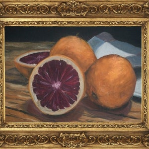K&ouml;nnte beinhalten: Ein Stillleben mit drei Orangen auf einem Holztisch. Eine Orange ist halbiert und zeigt ein tiefrotes Fruchtfleisch. Die Orangen sind in einer Gruppe angeordnet, wobei die geschnittene Orange in der Mitte liegt.
