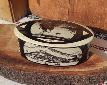 Oval black and white chocolate tin with a picture of a sailboat and old maps from the 50s
