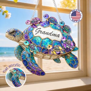 May include: A decorative acrylic turtle with a mosaic design in shades of blue, purple, and green. The word "Grandma" is displayed on the turtle's shell, surrounded by smaller turtles with names. The image includes a "Made in USA" sticker.