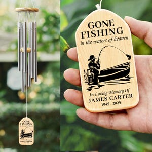 May include: Wooden memorial wind chime with a wooden plaque that reads "Gone Fishing in the waters of heaven. In Loving Memory of James Carter 1945-2025". The plaque features a silhouette of a person fishing in a boat.