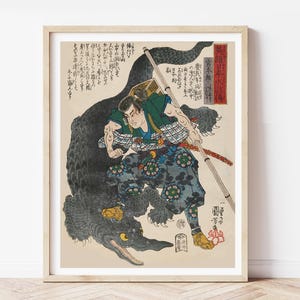May include: A Japanese woodblock print depicting a samurai warrior fighting a large black creature, possibly a demon or mythical beast. The warrior is wearing traditional armor and wielding a sword. The print is in black, white, and red tones.